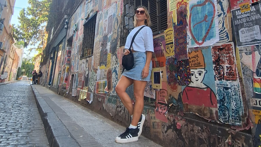 Natalia en una calle empedrada con murales urbanos